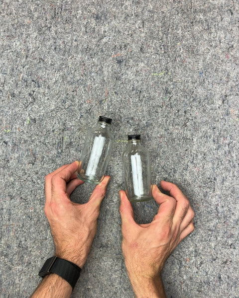 Two Small Clear Glass Bottles with Black Lids