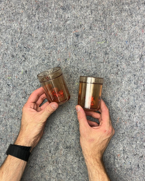 Two Plastic Cups With Confetti Floating In Water Around Them