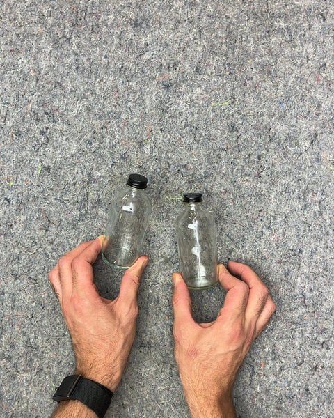 Two Small Clear Glass Bottles with Black Lids