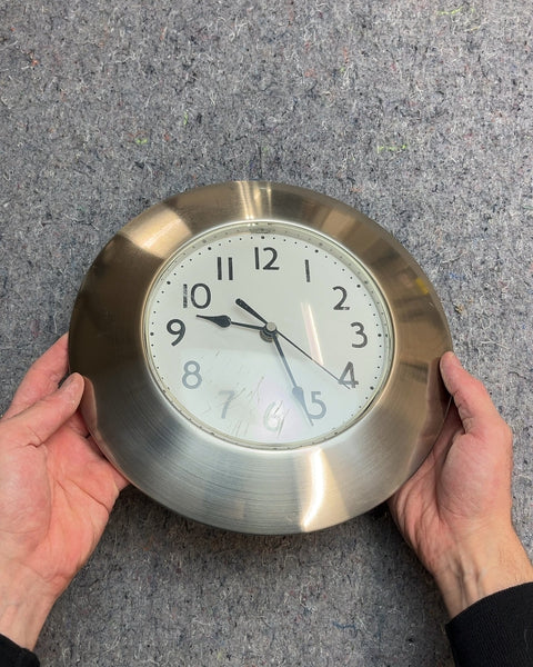 Round Silver Wall Clock With A Light Scratches At The Bottom